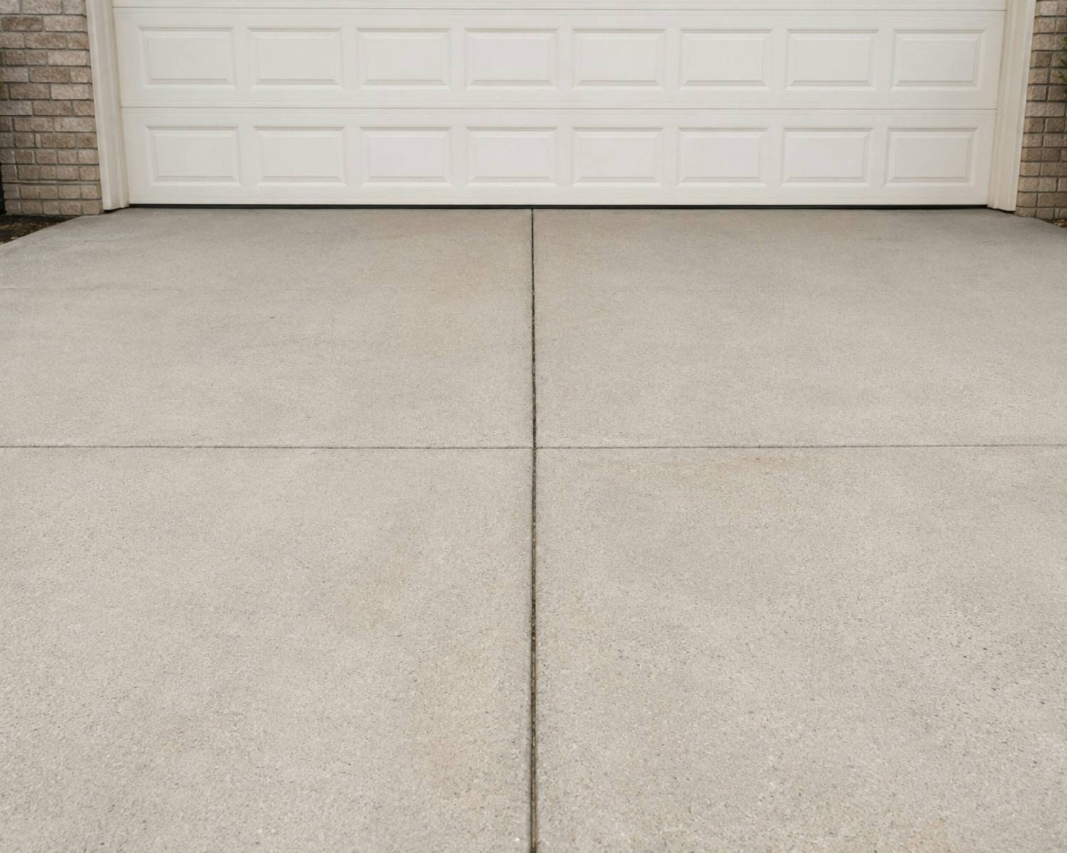Freshly poured concrete driveway in front of a garage